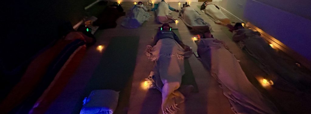 Candlelit group breathwork session, participants resting under soft candlelight